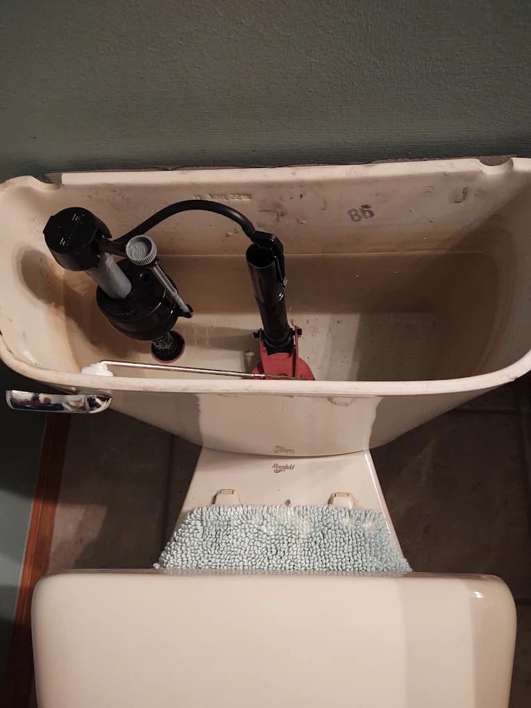 Inside a toilet tank showing the fill valve and flapper — common toilet repair parts in Southeast Michigan