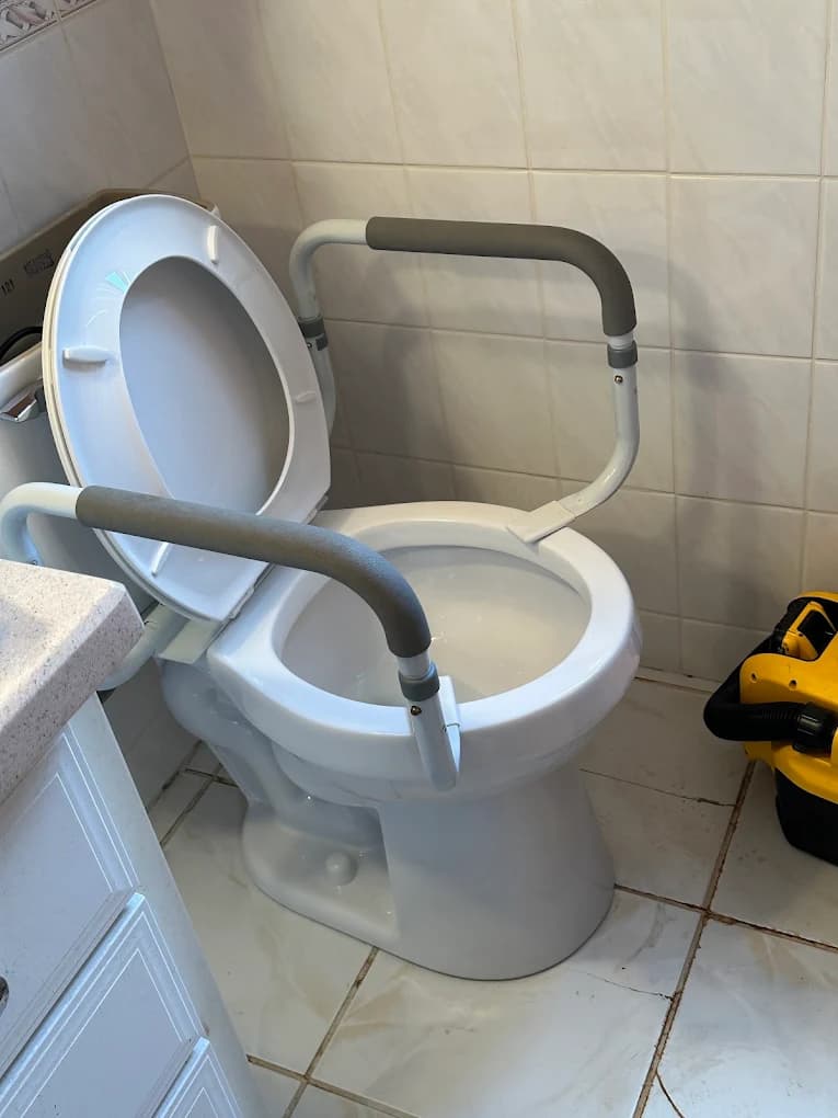 Comfort height toilet with safety grab rails installed — ADA-compliant toilet installation in Leonard